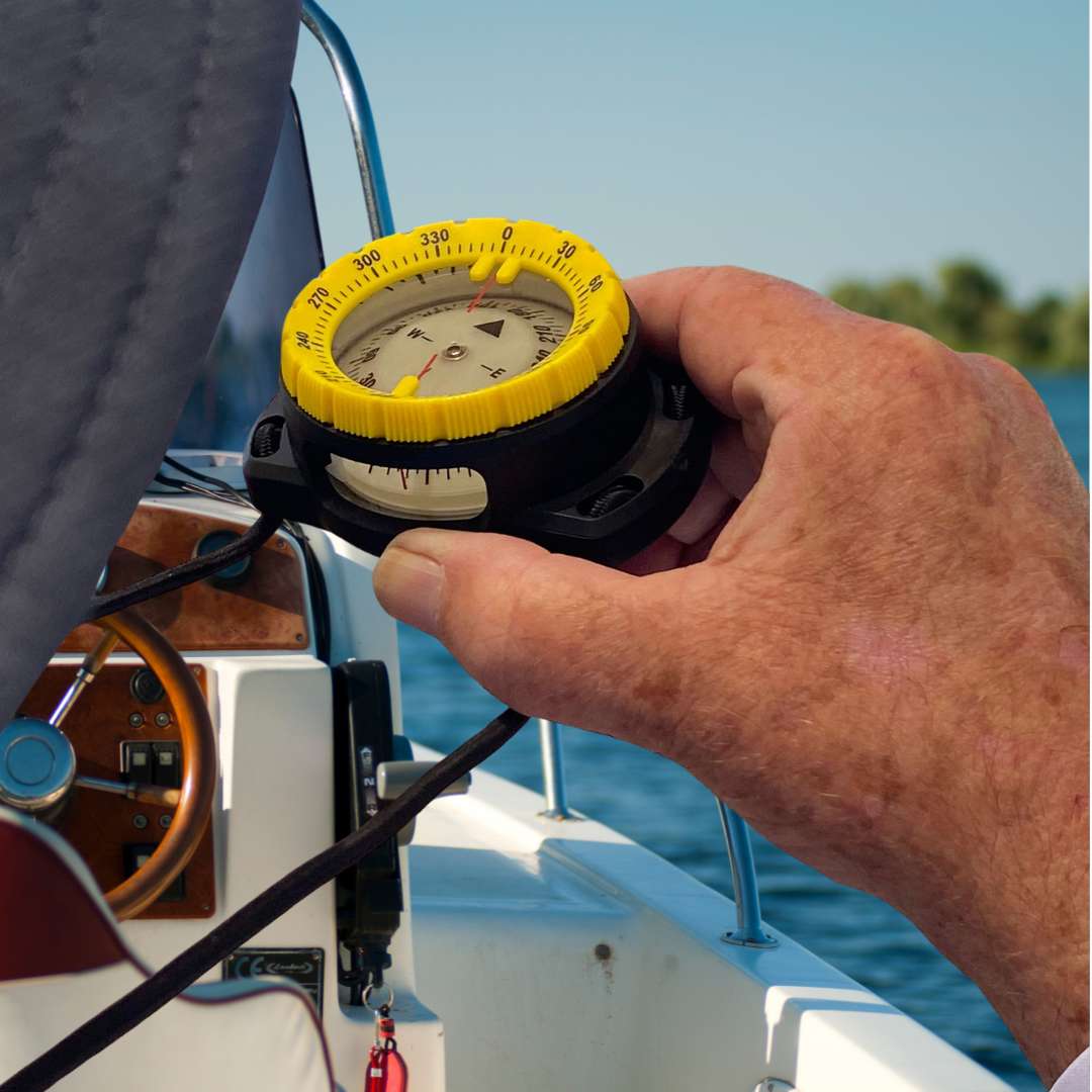 Handheld bearing compass on a boat with a clear sky background