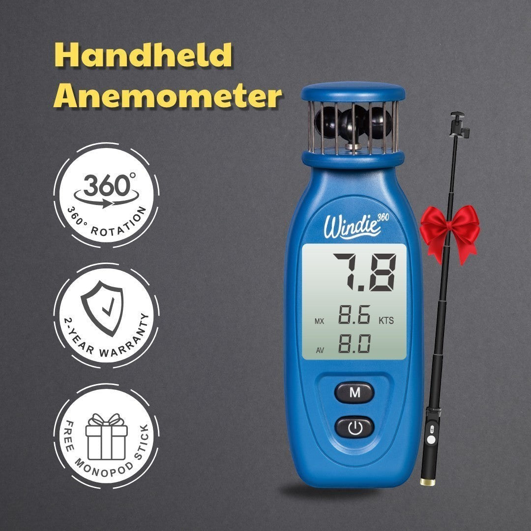 windie.pro blue handheld anemometer displaying wind speed, held by a person on a boat with sailboats in the background.