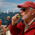 Windie.pro yellow pea-less whistle with rust-resistant metal grip and neck lanyard, used by a man on a boat.
