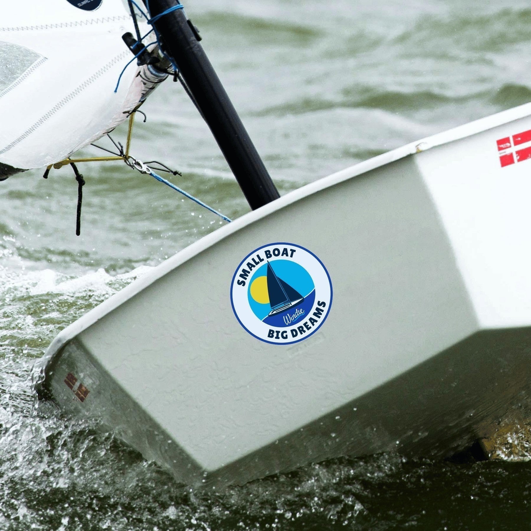 windie.pro round sticker with a sailboat graphic, sun, and text "SMALL BOAT BIG DREAMS"