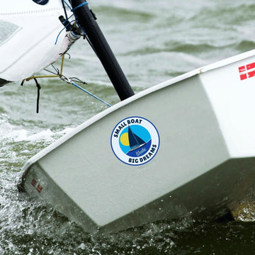 windie.pro round sticker with a sailboat graphic, sun, and text "SMALL BOAT BIG DREAMS"