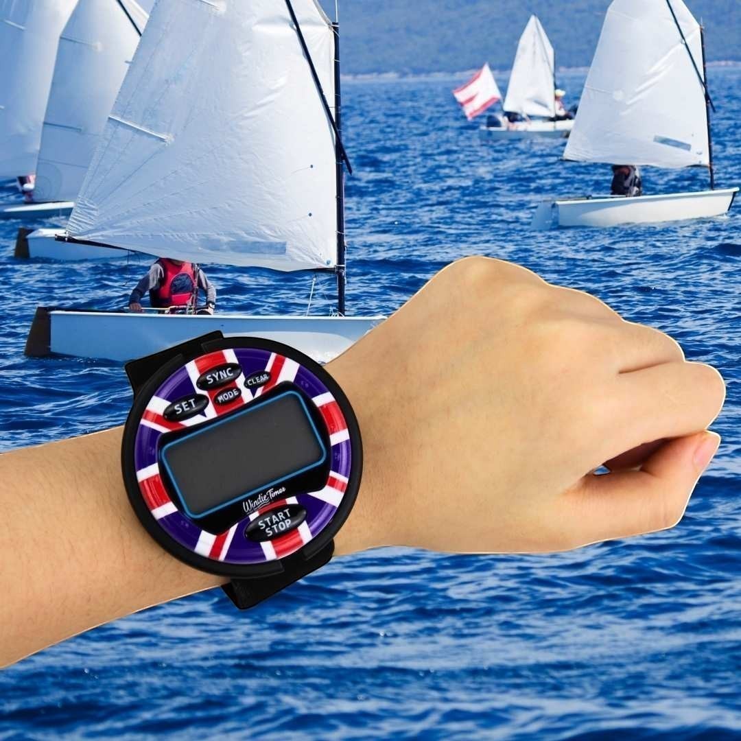 Windie.pro sailing timer watch with Union Jack design on wrist, featuring sync, mode, set, clear, start, and stop buttons. Digital display shows race timing.