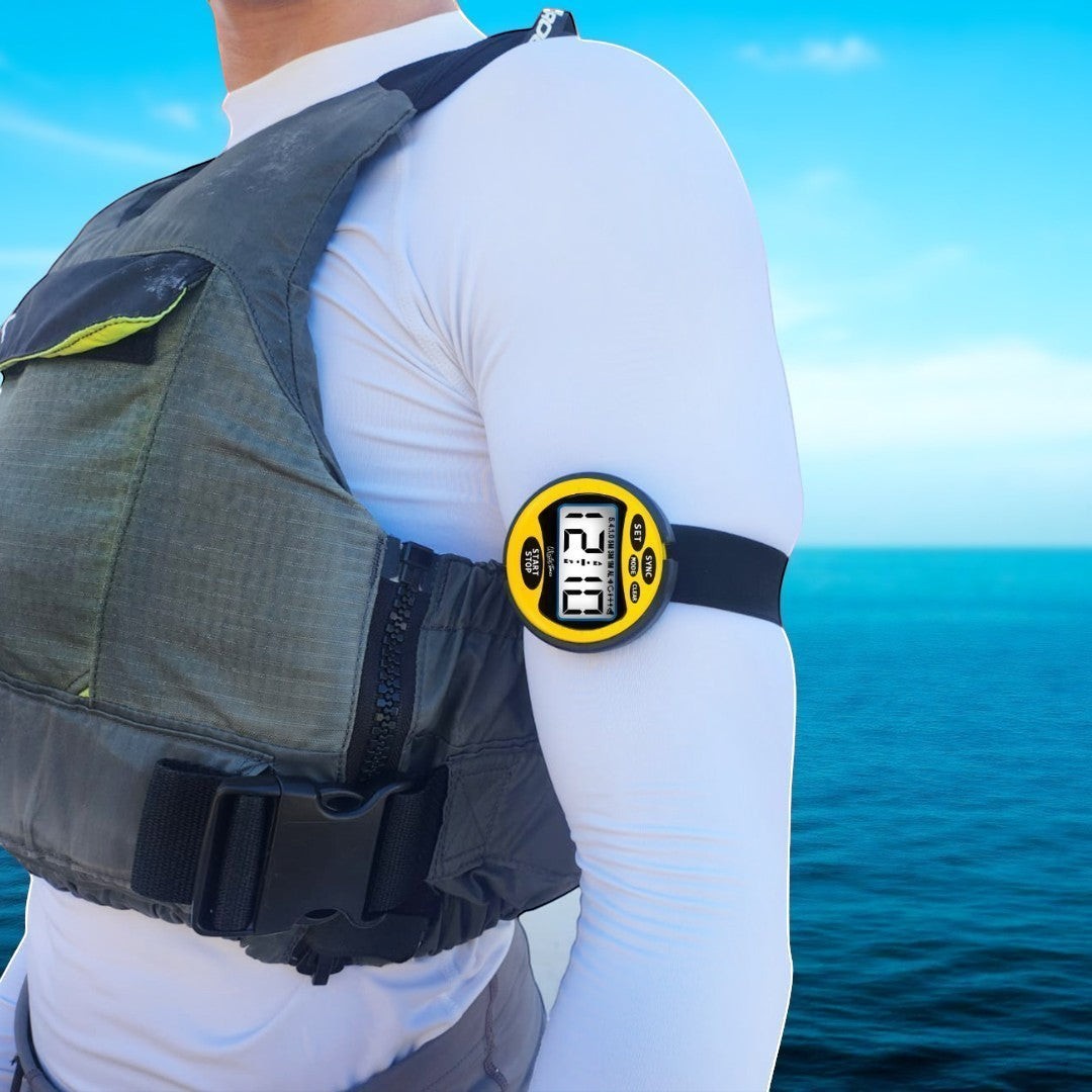Windie.pro yellow sailing timer stopwatch with digital display, worn on arm over white sleeve and grey life vest, with blue ocean background.